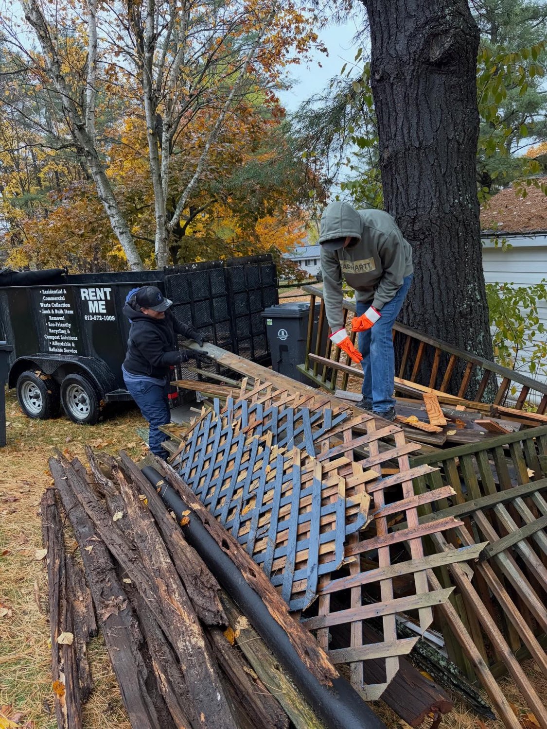 Crew members dismantling an old deck and lattice fence and loading it into the trailer