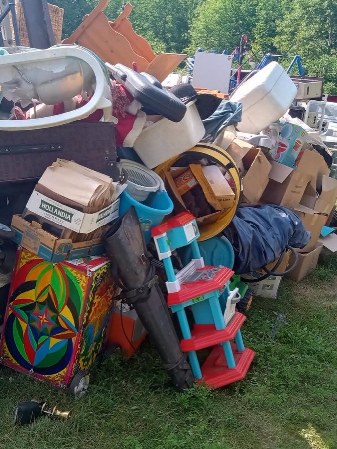 A large pile of household items and boxes staged on a lawn for an estate cleanout